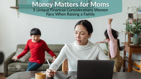 Mother reviewing family finances at kitchen table with laptop and coffee.