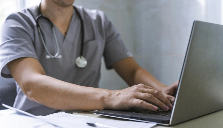 side-view-doctor-with-stethoscope-working-laptop-1